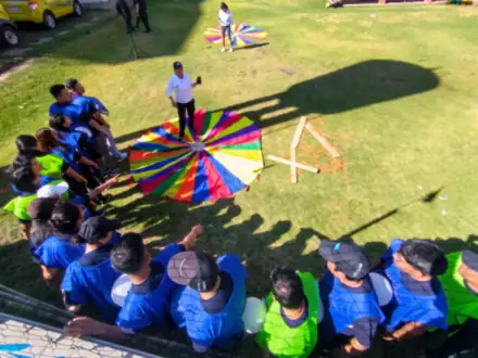 Vista desde arriba de un equipo con chalecos de colores alrededor de un paracaídas.