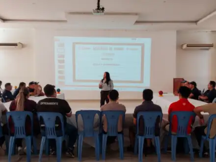Taller en un salón: la facilitadora expone frente a mesas en U.