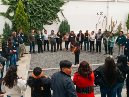 Equipo en círculo en un patio de piedra, en una dinámica de presentación.