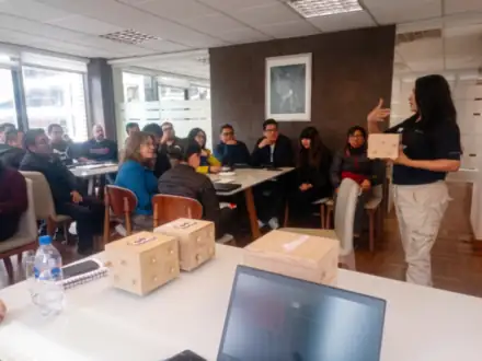 Capacitación en oficina: la facilitadora conversa con el equipo sentado en mesas.