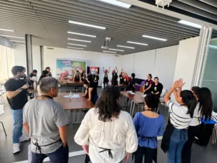 Equipo de pie con las manos en alto en una sala de capacitación.